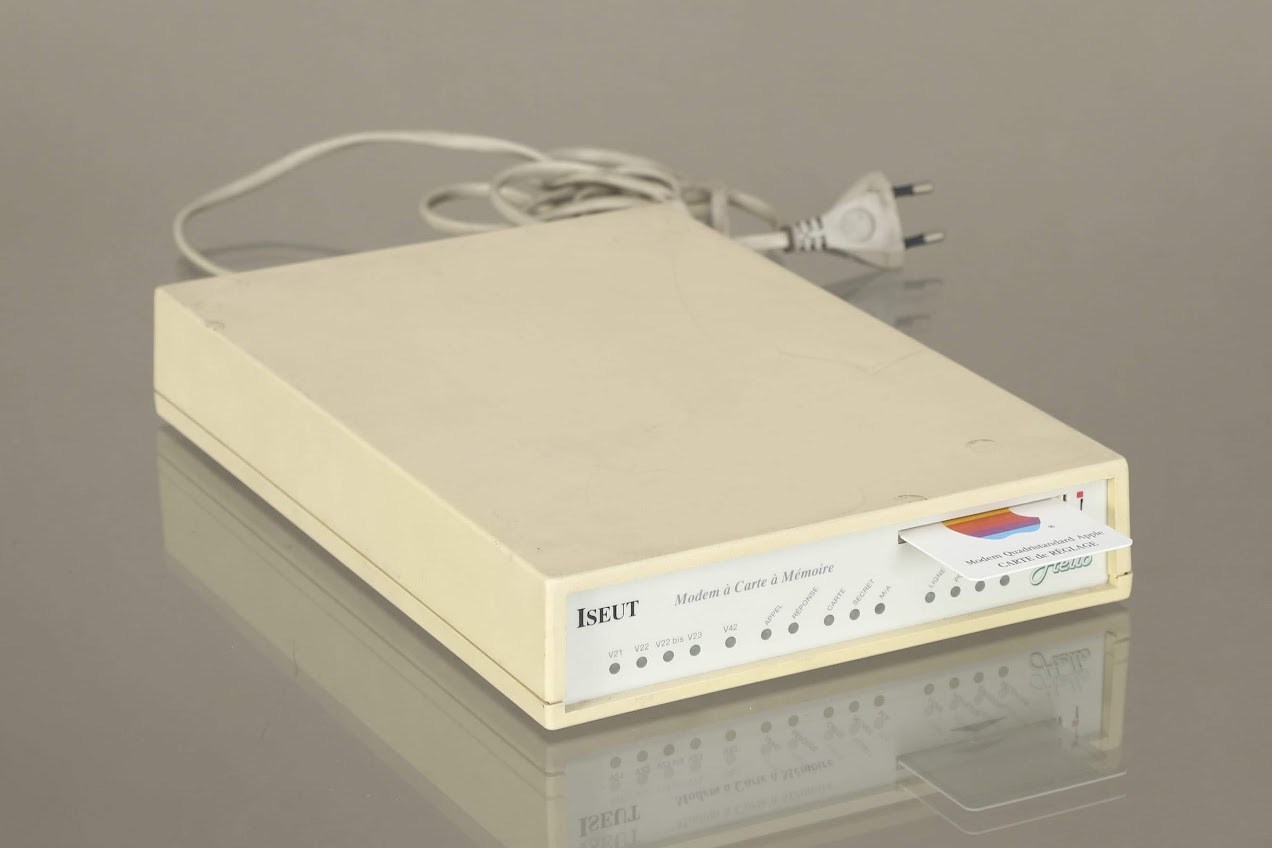 Modem “ISEUT” et sa carte à puce siglée Apple, 1984<br /><br />Conçue par la société Hello, fondée par Roland MORENO au début des années 1980, ce modem fonctionnait avec une carte à puce destinée à sécuriser son utilisation. Commercialisé comme périphérique pour les ordinateurs Macintosh, “Iseut” a été au catalogue d’Apple tout au long des années 1980. Parmi les usages permis par ce modem : pouvoir créer un groupe sécurisé d’utilisateurs, se connecter à un minitel.... La vente de ce modem “Iseut” (qui existait aussi dans une version nommée “Tristan”), a permis à la société de Roland MORENO de toucher des revenus avant le succès mondial de la télécarte.<br /><br />H. 4.5 cm L. 28 cm P. 18.5 cm